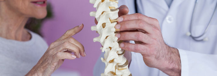 Doctor reviewing a spine model with a patient experiencing back pain